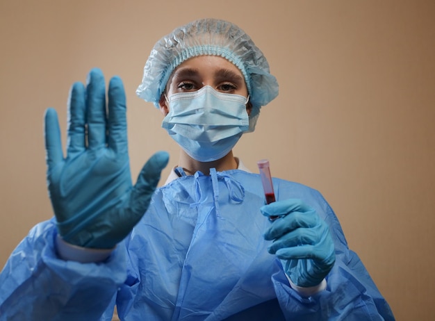 Un'infermiera tiene una provetta con un campione di sangue positivo al coronavirus e mostra un segnale di STOP
