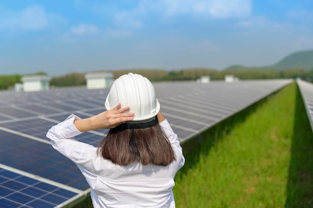 Un ingegnere donna che indossa un casco in una fattoria di celle fotovoltaiche o in pannelli solari