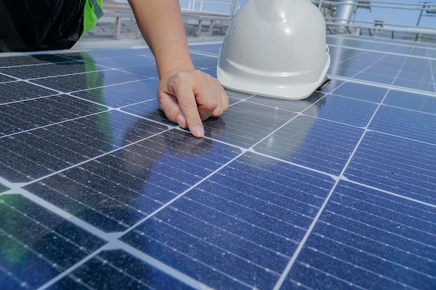 Un ingegnere elettrico che indossa un cappello bianco sta controllando. Pulizia dei pannelli solari sul tetto dell'edificio.