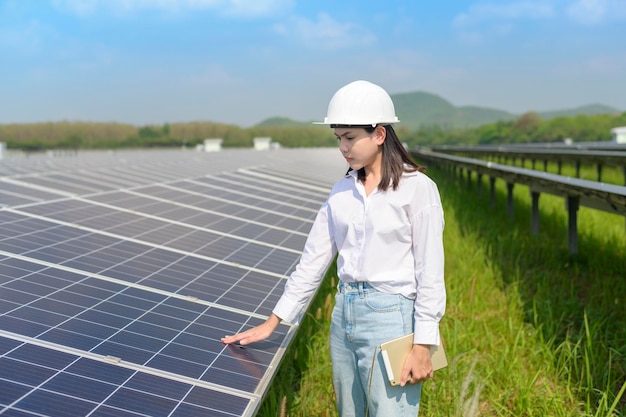 Un ingegnere femminile che indossa il casco in una fattoria di celle fotovoltaiche o in un campo di pannelli solari