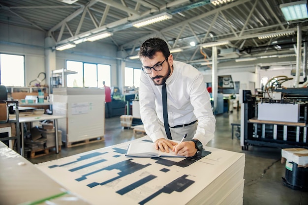 Un ingegnere grafico che annota i calcoli per i supporti di stampa presso la tipografia