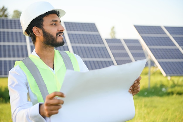 Un ingegnere indiano con un giubbotto verde sta lavorando su un campo di pannelli solari il concetto di energia rinnovabile