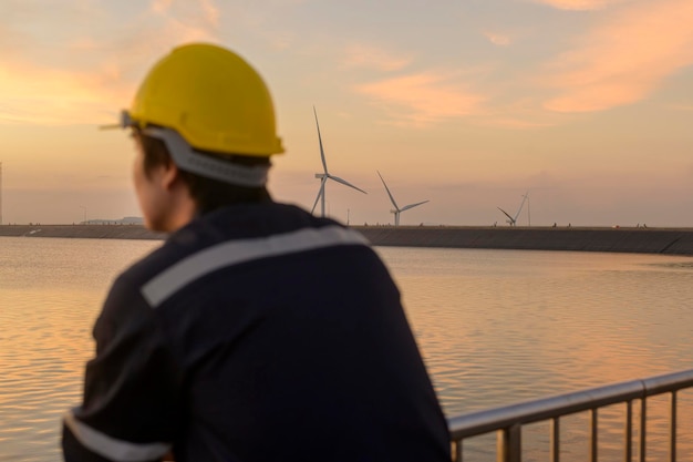 Un ingegnere maschio che indossa un casco protettivo al tramonto, fuoco selettivo sullo sfondo