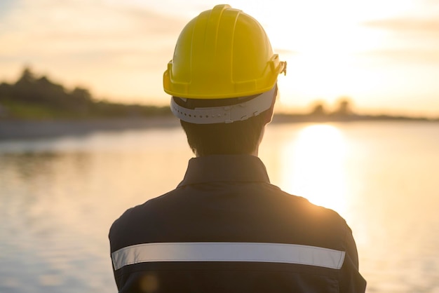 Un ingegnere maschio che indossa un casco protettivo al tramonto.