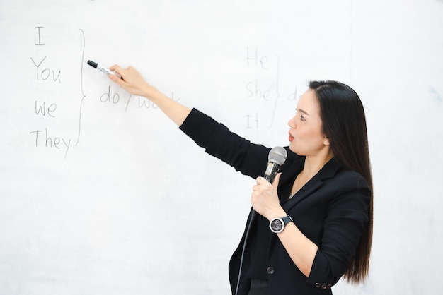 Un'insegnante asiatica di mezza età tiene il microfono nella lavagna dell'aula all'università