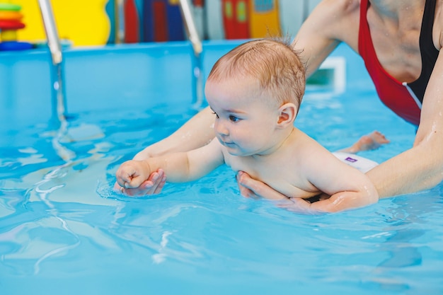 Un insegnante di nuoto insegna a un ragazzino a nuotare in piscina Le prime lezioni di nuoto per bambini Sviluppo per neonati