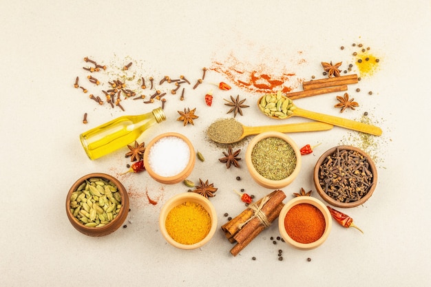 Un insieme di spezie per cucinare il curry. Condimenti aromatici: curcuma, paprika, cardamomo, cannella, anice stellato, peperoncino, pepe nero, erbe secche, sale. Sfondo di pietra chiara in cemento, vista dall'alto