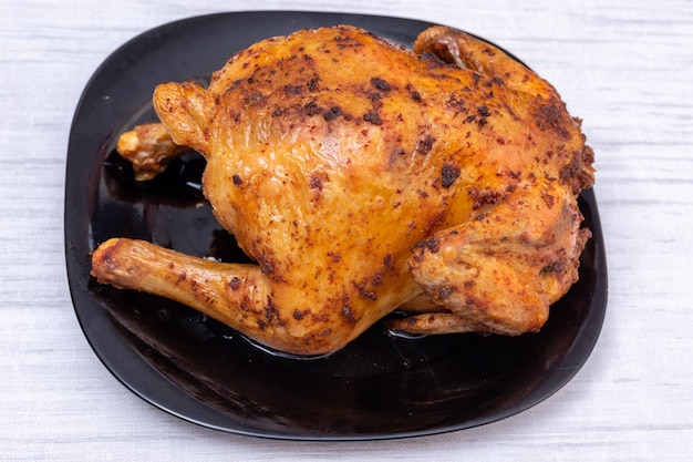 Un intero pollo o tacchino fritto su un piatto nero sul tavolo, vista dall'alto. Pollo con una crosta croccante marrone. Pollo fatto in casa. Cibo tradizionale di Natale. giorno del Ringraziamento