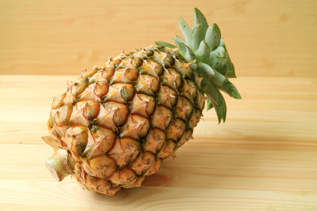 Un isolato intero della frutta fresca matura di ananas su fondo di legno