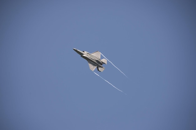 Un jet da combattimento sta volando nel cielo con uno sfondo di cielo blu.