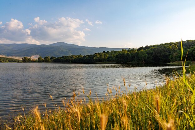 Un lago riflette la luce solare contro il cielo blu e le catene montuose e i villaggi