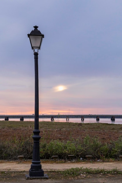 Un lampione con il sole che tramonta dietro di esso