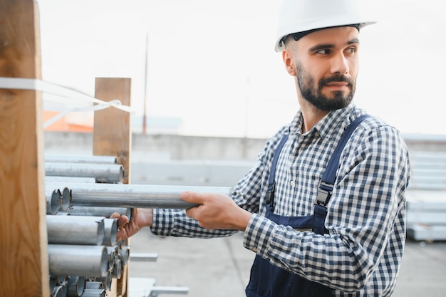 Un lavoratore detiene tubi metallici in un magazzino di fabbrica Laminazione di metalli