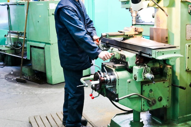 Un lavoratore di sesso maschile lavora su un'attrezzatura per tornio per fabbro in ferro metallico più grande per riparazioni di lavori in metallo