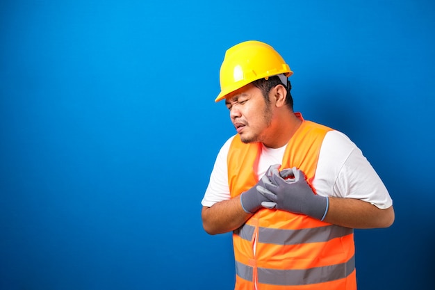 Un lavoratore grasso asiatico che indossa un casco di sicurezza sente dolore al petto