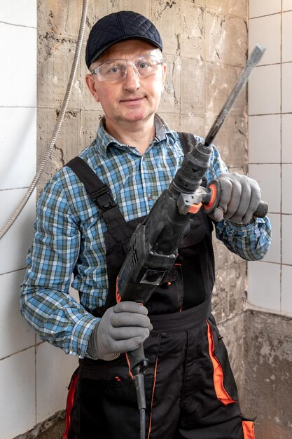 Un lavoratore in tuta e occhiali protettivi tiene in mano un perforatore