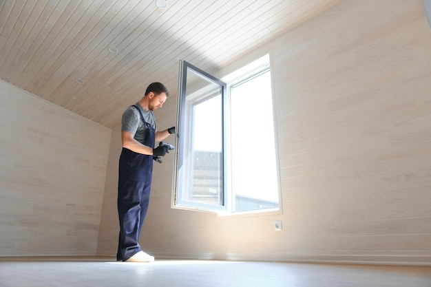 Un lavoratore installa le finestre in una nuova casa modulare Il concetto di una nuova casa