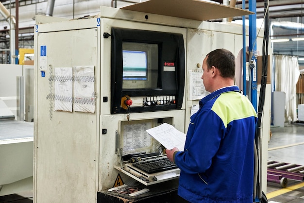 Un lavoratore lavora pezzi grezzi di mobili su una macchina utensile in una fabbrica. Produzione industriale di mobili.