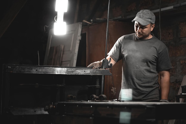 Un lavoratore prepara una macchina per la lavorazione del legno per il lavoro nella sua officina domestica Realizzazione di prodotti in metallo con le proprie mani