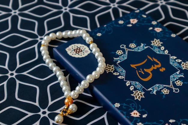 Un libro di Surah Yaseen o Yasin e perle di preghiera su un tappetino di preghiera
