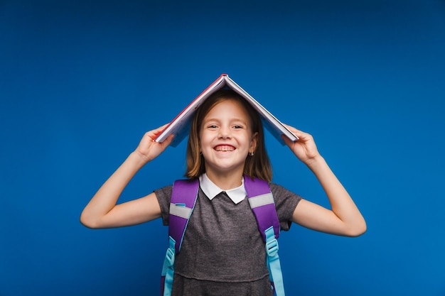 Un libro tetto sopra la tua testa Una bambina tiene un libro di testo sulla sua testa Una bambina con un libro su uno sfondo arancione