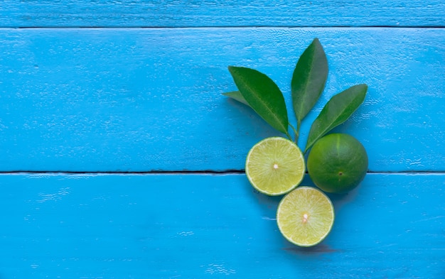 un limone di lime è mezzo tagliato su fondo di legno blu