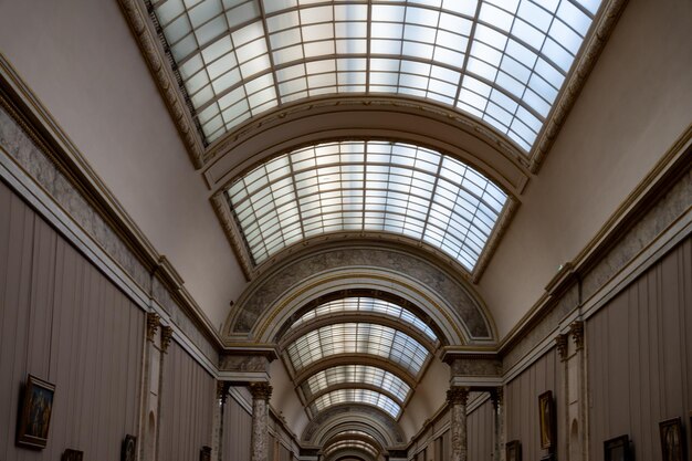 Un lungo corridoio con un soffitto bianco e una fila di dipinti sulle pareti