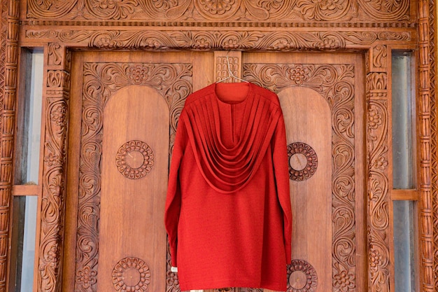 un maglione rosso appeso a una porta di legno con un maglione Rosso appeso su di esso