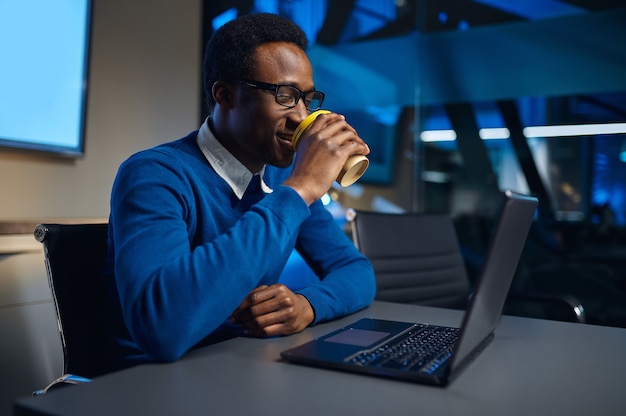 Un manager con gli occhiali lavora su un laptop nell'ufficio notturno