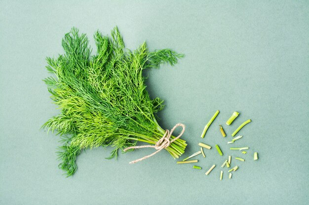 Un mazzetto di aneto fresco e le estremità tagliate degli steli su uno sfondo verde. Verdure vitaminiche in una dieta sana. Vista dall'alto