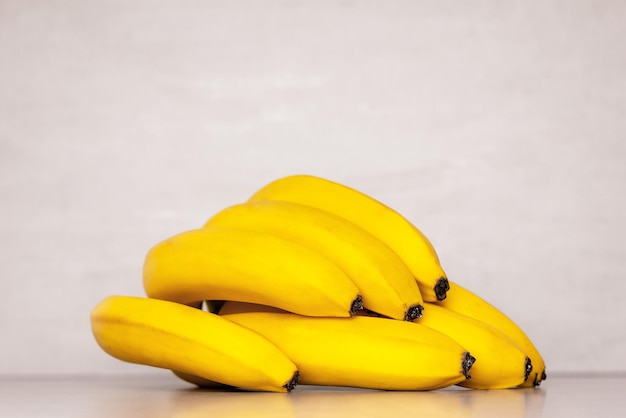 Un mazzo di banane mature gialle su uno sfondo grigio primo piano