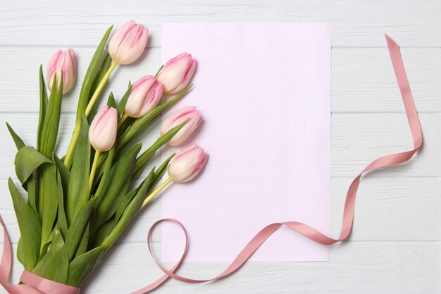 Un mazzo di bellissimi tulipani e un regalo su uno sfondo di legno vista dall'alto