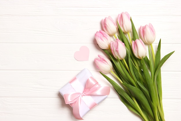 Un mazzo di bellissimi tulipani e un regalo su uno sfondo di legno vista dall'alto