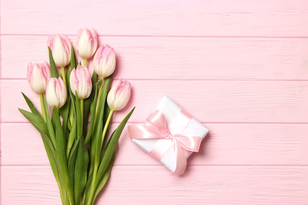 Un mazzo di bellissimi tulipani e un regalo su uno sfondo di legno vista dall'alto