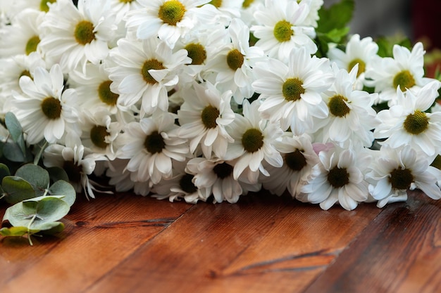 Un mazzo di crisantemi bianchi giace su un tavolo di legno