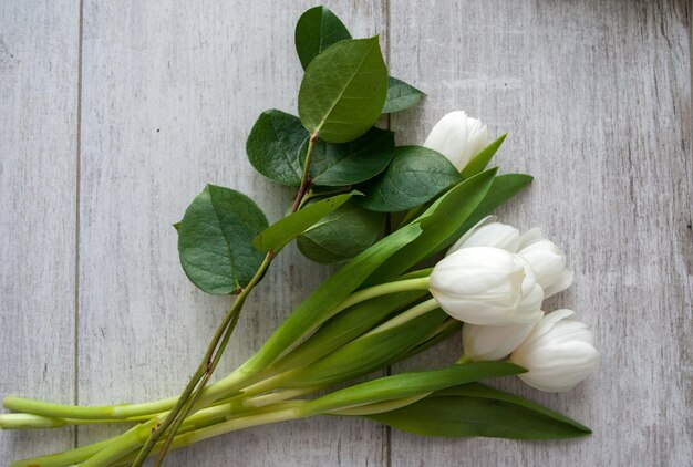 un mazzo di fiori bianchi con foglie verdi su un tavolo di legno.