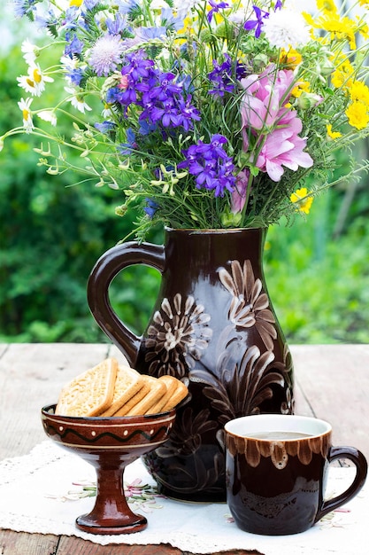 Un mazzo di fiori, tè e biscotti sul tavolo in giardino