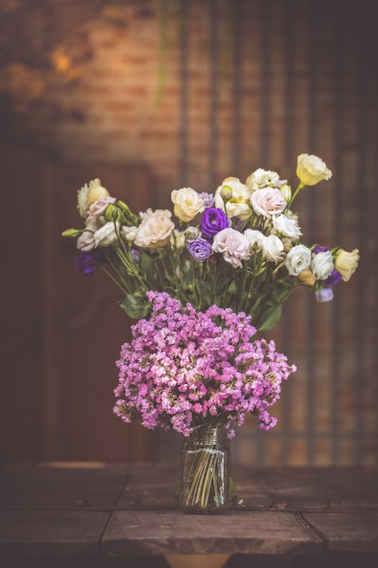 Un mazzo di fiori viola in un vaso di vetro su un pavimento in legno di vecchi vintage.