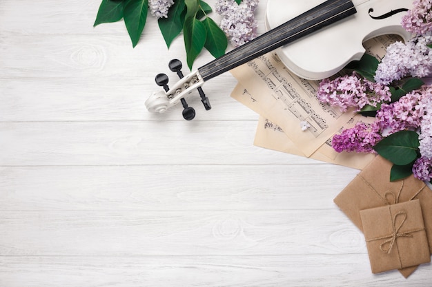 Un mazzo di lillà con violino, lettera e foglio di musica su un tavolo di legno bianco. Top wiev con spazio per il testo