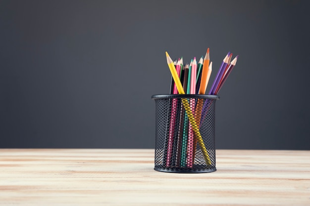 Un mazzo di matite colorate in uno stand su una scena grigia