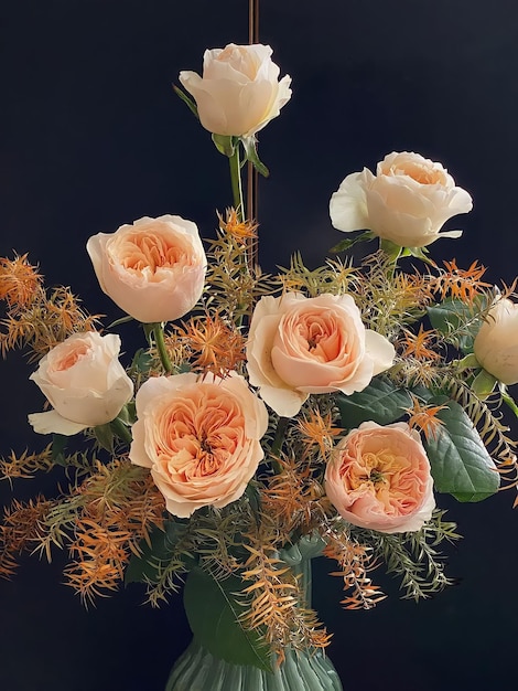 Un mazzo di rose con fiori d'arancio e foglie verdi.