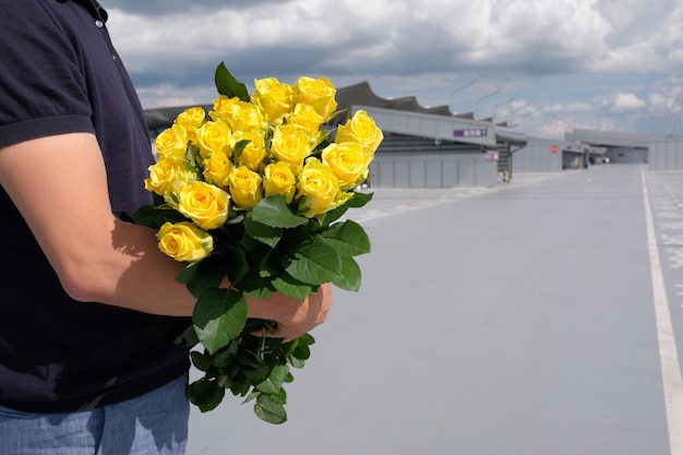 Un mazzo di rose gialle nelle mani di un uomo nel parcheggio