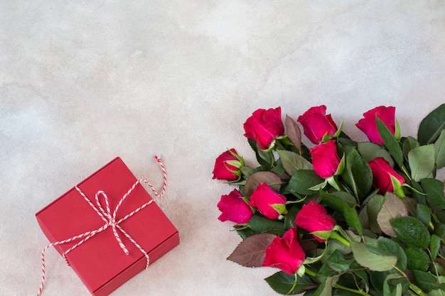 un mazzo di rose rosse e una confezione regalo rossa