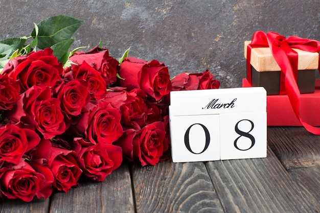 un mazzo di rose rosse, regali in una scatola e la data dell'8 marzo
