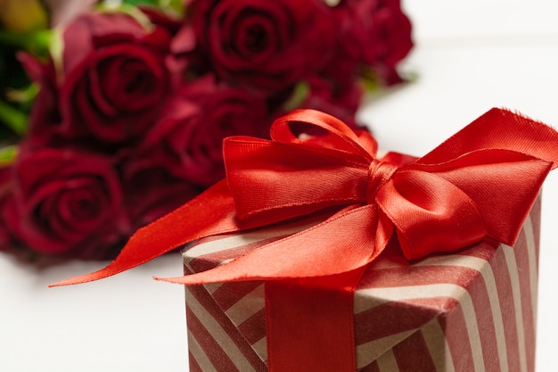 Un mazzo di rose rosse, regalo e cuori sul tavolo. Concetto Festa della donna o San Valentino. Copia spazio