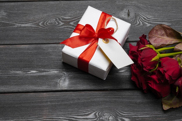 Un mazzo di rose rosse, regalo e cuori sul tavolo. Concetto Festa della donna o San Valentino. Copia spazio