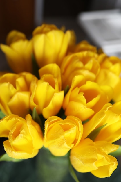 Un mazzo di tulipani gialli freschi in un vaso su un tavolo vicino alla finestra