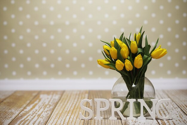 Un mazzo di tulipani gialli in un vaso sul pavimento. Un regalo per la festa della donna dai fiori di tulipano giallo. Bellissimi fiori gialli in un vaso da parete.