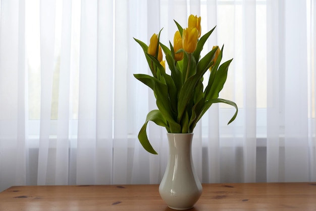 Un mazzo di tulipani gialli in un vaso sul tavolo