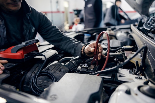 Un meccanico automobilistico sta eseguendo la diagnostica della batteria su un'auto presso il negozio del meccanico